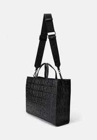 Bolso tote rectangular negro con diseño de logotipo en relieve, acabado texturizado, asas superiores dobles y correa de hombro ajustable.