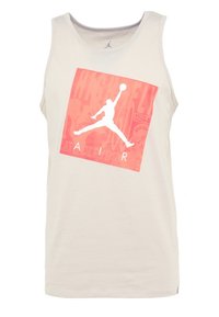 Ljust beige linne i bomull med en röd grafisk fyrkant som har en vit silhuett och texten "AIR". Designen har en rund halsringning.