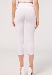 Leggings capri blancos con cintura alta, hechos de un tejido suave y elástico. Textura lisa, silueta ajustada y dobladillo a la altura del tobillo.