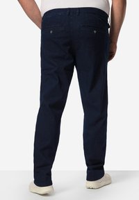 Tummansiniset farkut, joissa on rento malli, kaksi takataskua napilla ja yksinkertainen vyötärönauhan muotoilu. Teksturoitu kangas ilman kuvioita.