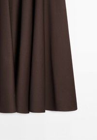Dark brown fabric curtain hanging with soft folds against a white background.