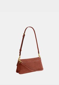Sac à épaule en daim marron avec bandoulière réglable, garnitures dorées et une étiquette de marque suspendue sur un côté.