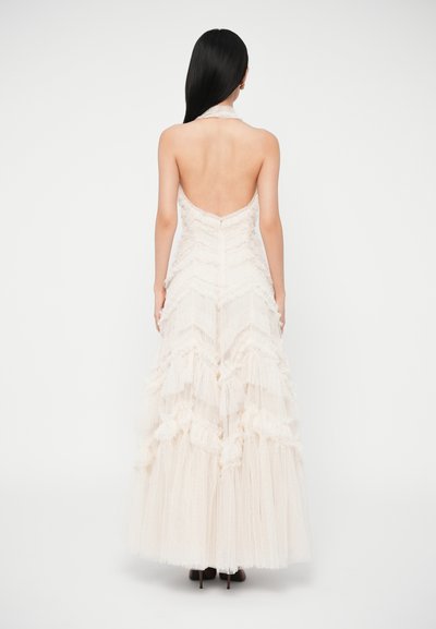 Biely šatový model s viacerými vrstvami a s halter krkom, zdobený volánikmi, so priliehavým živôtikom a splývavou sukňou, vyrobený z ľahkej textúrovanej tkaniny.