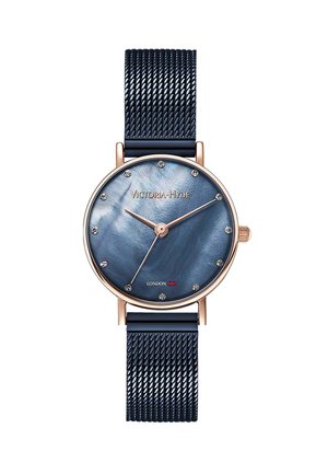 Reloj de pulsera redondo con esfera azul de nácar, caja de oro rosa, marcadores horarios de cristal y correa de malla metálica texturizada en azul oscuro.