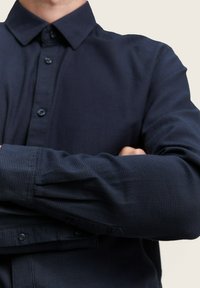 Sötétkék gombos ing, texturált kockás mintával, masszív gallérral és gombos mandzsetta résszel, sima anyagból készítve.