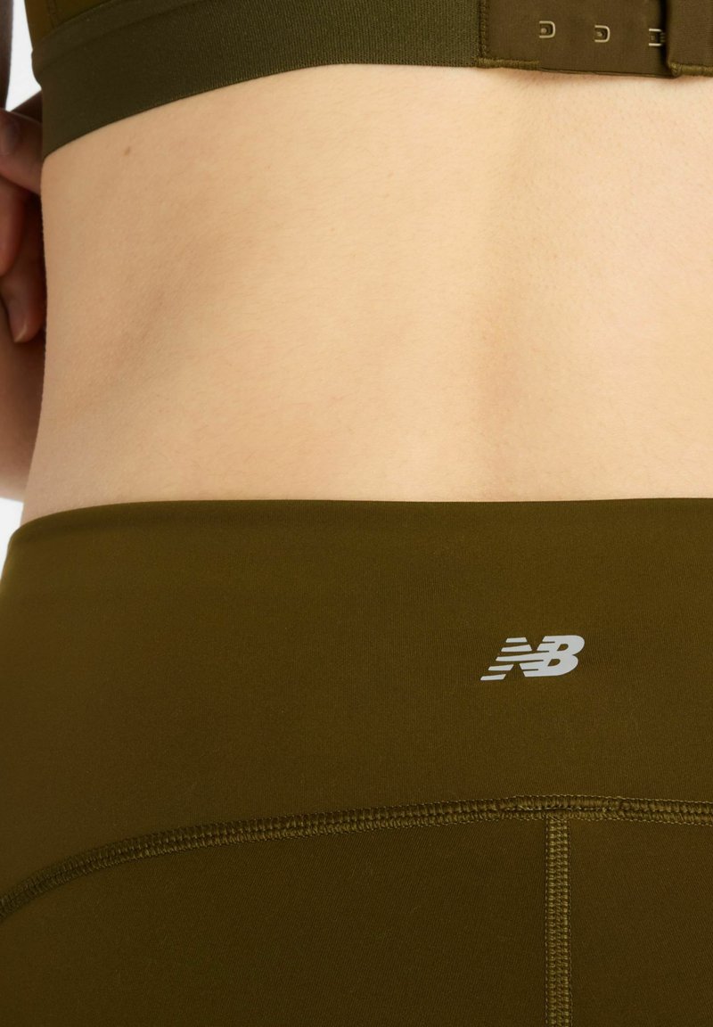 Olivgrön sport-bh och matchande högmidjade leggings med flatlock-sömmar och en liten vit logotyp på midjebandet.