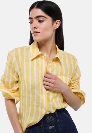Chemise à boutons rayée jaune en tissu léger, présentant des rayures blanches horizontales, un col et des manches retroussées.