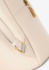 Beżowa skórzana torebka o gładkiej fakturze, z zapięciem na zamek i złotymi detalami. Posiada metkę marki oraz starannie przeszyte krawędzie.