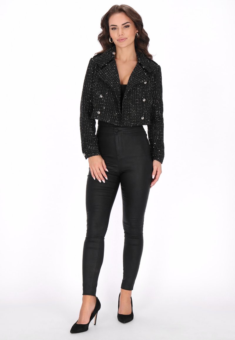 Zwarte cropped tweedjas met dubbele knopen, gecombineerd met hoge, zwarte skinny pants en zwarte puntige hakken.