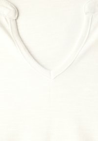 T-shirt en coton blanc avec un décolleté en V. Le tissu présente une texture subtile et est léger, adapté à une tenue décontractée.