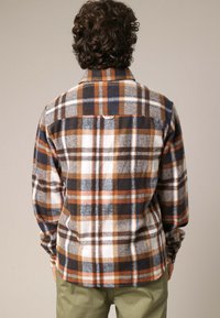 Bruin en marineblauw geruite flanellen overhemd met lange mouwen, voorzien van een zachte textuur, knopenmanchetten en een rechthoekig rugpanddetail.