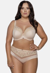 Completo di lingerie beige composto da un reggiseno con dettagli in pizzo e ferretto, abbinato a perizoma che presenta pannelli laterali trasparenti e dettagli floreali.