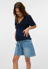 Jūras spēku apakšveļa ar īsām piedurknēm, kas apvienota ar gaiši ziliem denim šortiem, kuriem ir sasietā josta. Mīksta tekstūra un ikdienišķs dizains.