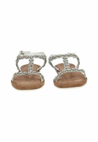 Ein Paar flache Sandalen mit braunen Wildlederfußbetten und silbernen Riemen, die mit mehrfarbigen Strasssteinen geschmückt sind, von vorne betrachtet.