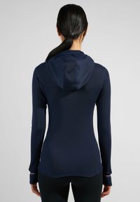 Marineblaue Langarm-Hoodie mit strukturiertem Oberflächenmaterial, taillierter Passform und Kapuze. Verfügt über kontrastierende farbige Akzente an den Ärmelbündchen.