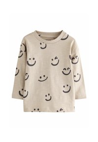 Chemise longue à manches beiges claires présentant un motif de visages souriants sombres et de clins d'œil. Tissu doux avec un col rond et des manches à poignets.
