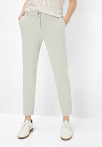 Pantalons gris clair ajustés avec une coupe slim, dotés d'une fermeture à bouton, de poches latérales et d'une texture lisse. Assortis à des baskets blanches.
