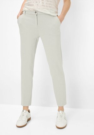 Lichtgrijze, op maat gemaakte broek met een slim fit, met een knoopsluiting, zijzakken en een gladde textuur. Gecombineerd met witte sneakers.
