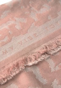 Rosa vävd tyg med ett subtilt upphöjt mönster och fransade kanter, med en präglad inskription som säger "MY VIBE 101."