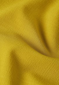 Geel textiel met een zachte, geweven uitstraling, gekenmerkt door subtiele variaties in tint en een gladde afwerking.