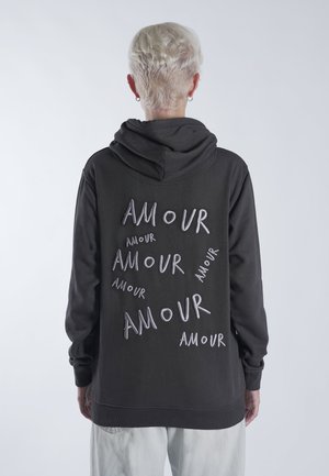 Black hoodie featuring multiple embroidered "AMOUR" text in varying orientations on the back. Soft fabric, spacious hood, and ribbed cuffs.