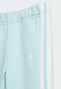 Miętowe dresy o miękkiej fakturze, z białymi paskami po bokach i białymi logo Adidas oraz Disney. Elastyczny pasek w talii.