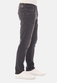 Jeans de mezclilla negra con un corte ajustado, que cuentan con cinco bolsillos, costuras visibles y una etiqueta de cuero en la cintura trasera.