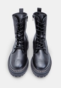 Botine din piele neagră până la gleznă, cu un design cu șireturi, fermoar lateral, talpă din cauciuc groasă și cusături contrastante pe margine.