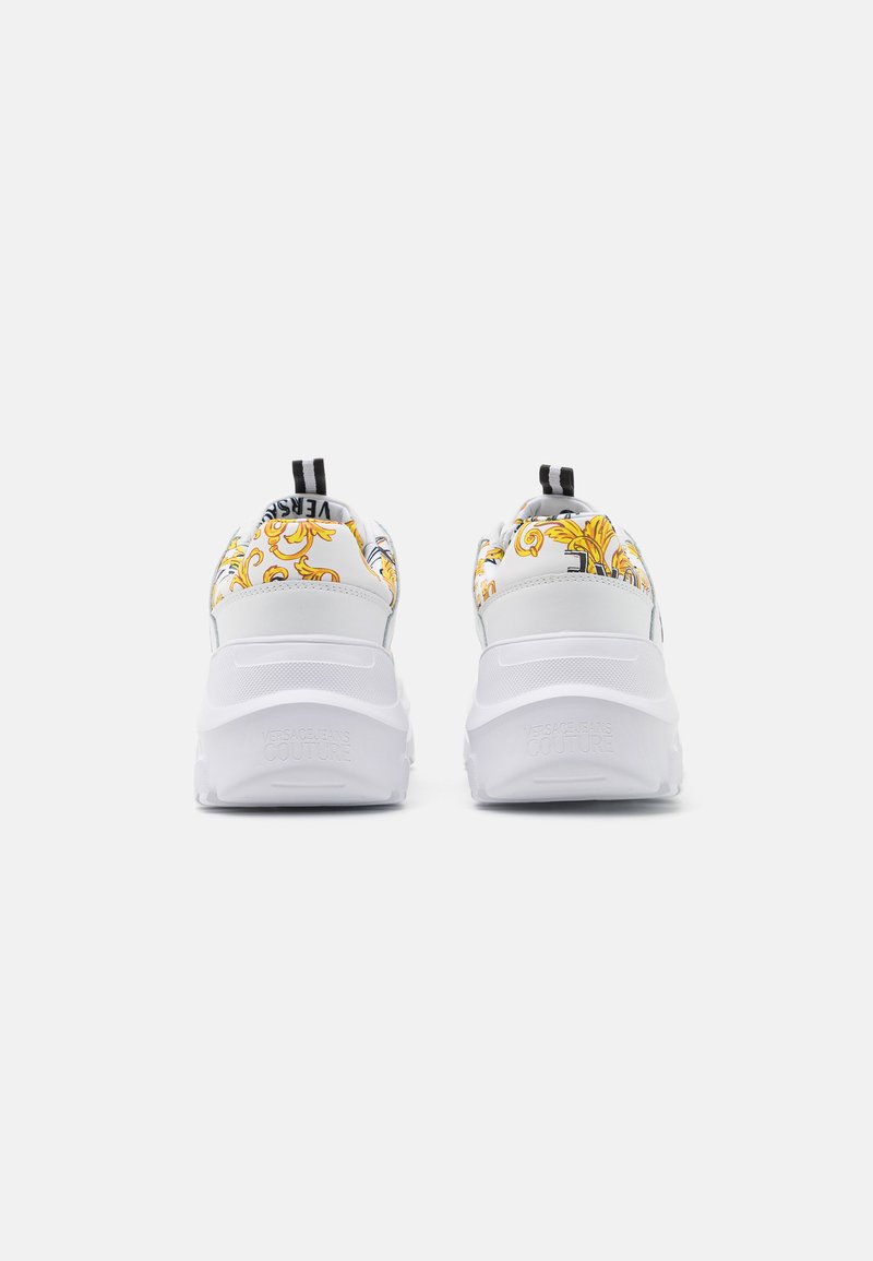 Sneakers bianchi con stampa barocca colorata sul tallone, dotati di passanti neri e suole in gomma texture; design elegante e moderno.