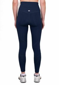 Leggings blu navy a vita alta con una texture liscia, caratterizzati da cuciture curve e dettagli del logo discreti sulla vita.