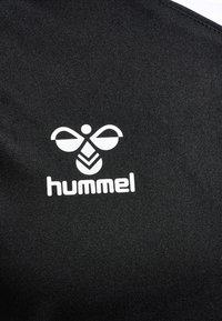 Zwart stof met een wit logo en een abstract ontwerp boven het woord "hummel." Gladde textuur en eenvoudig ontwerp.