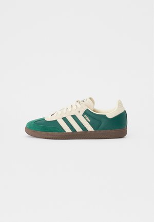 Sneaker Adidas Samba verde e crema con suola marrone, presenta tre strisce crema e la scritta "Samba" sul lato.
