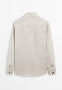 Helles beige Langarmhemd mit Kragen, strukturiertem Stoff, Knöpfen an den Manschetten und einem mittigen Rückenschlitz.