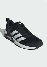 Black athletic shoe with a textured knit upper, three white stripes on the side, and a cushioned white sole. Features a pull tab at the back.