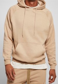 Beige hoodie met een trekkoordkap, raglanmouwen, een voorzak en ribgebreide manchetten. Heeft een zachte, gestructureerde stofafwerking.