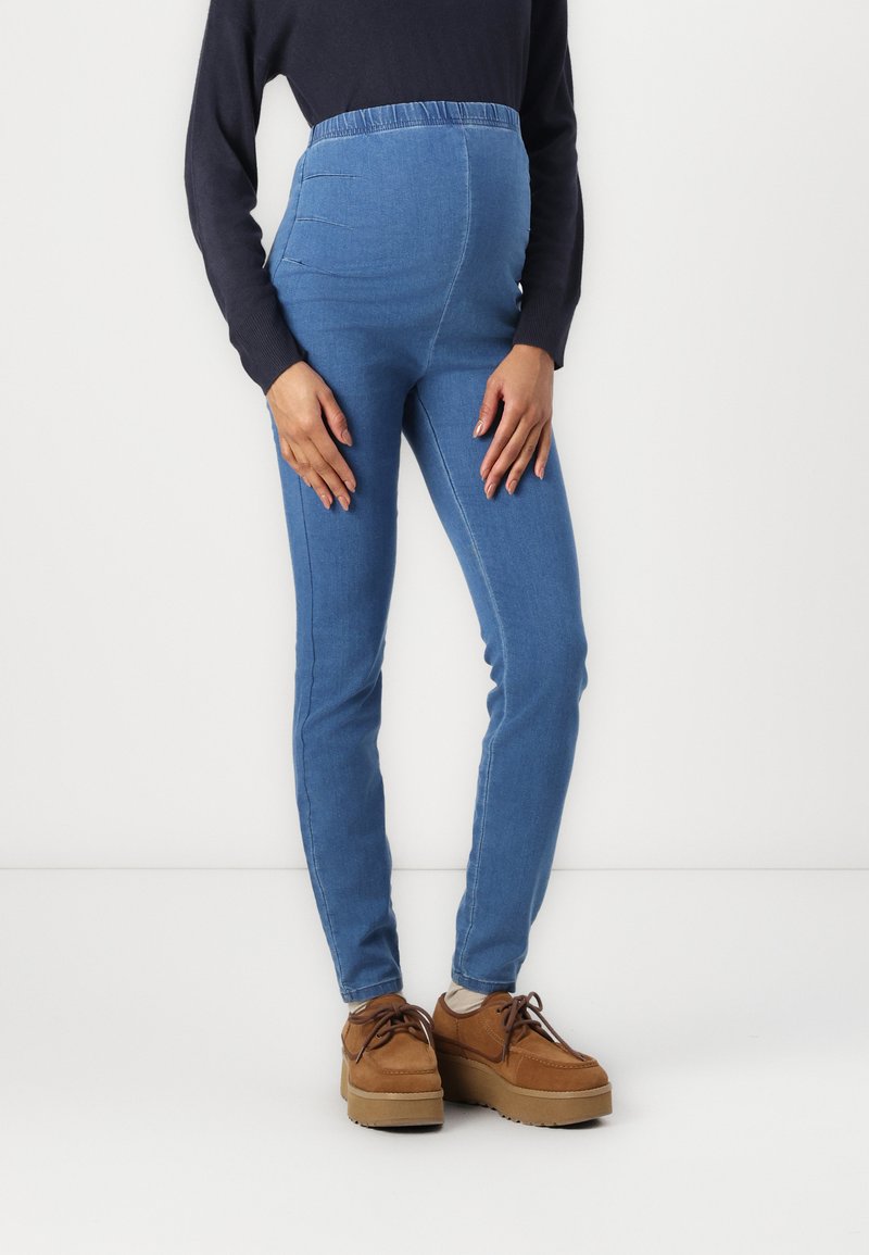 Világoskék denim várandós leggings, elasztikus derékpánttal, karcsú fazonnal és sima textúrával, barna platform cipőkkel párosítva.