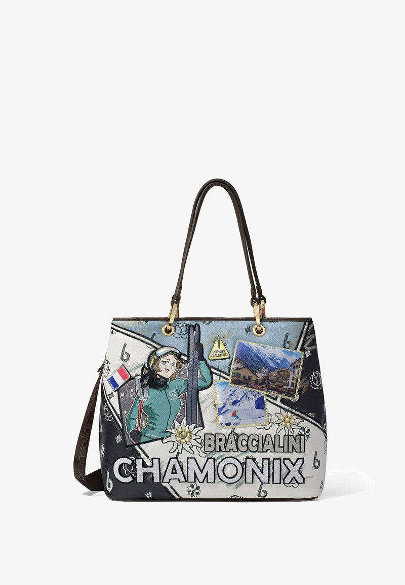 Tasje met grafisch ontwerp, voornamelijk blauw en wit, met skithema's, een karakterillustratie en decoratieve patches. Bruine handvatten.