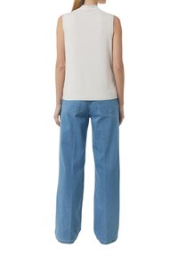 Koszulka bez rękawów w jasnoróżowym kolorze, okrągły dekolt, połączona z szerokimi niebieskimi dżinsami, posiadającymi dwie tylne kieszenie i luźny krój.