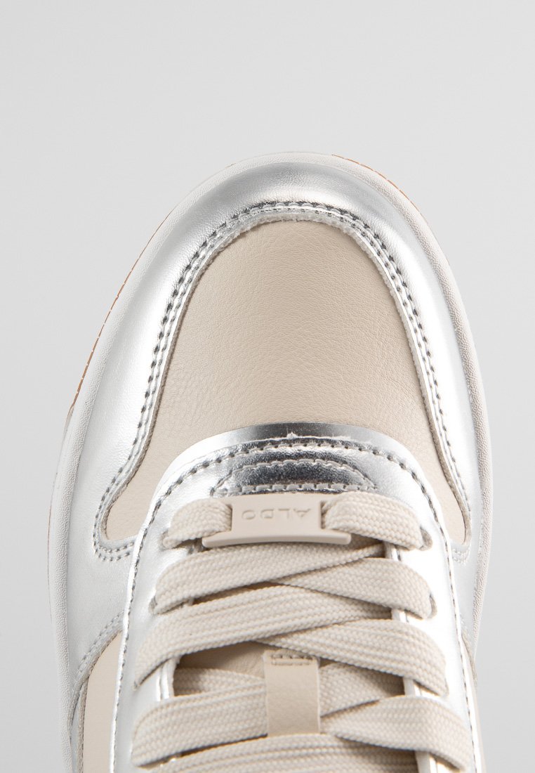 Baskets avec un embout en métal argenté et une tige en cuir beige. Comprend des lacets de couleur claire et une semelle en caoutchouc pour une bonne adhérence.