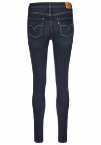 Jeans ajustados de denim oscuro con una textura suave, que presentan dos bolsillos traseros y detalles de costura amarilla. Etiqueta de marca de cuero en la cintura.