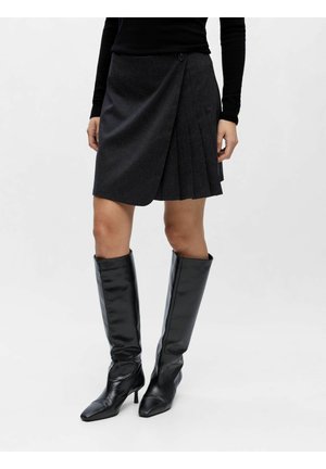 Gonna a portafoglio plissettata grigio scuro con un dettaglio di un singolo bottone, abbinata a stivali neri al ginocchio con punta a stiletto, texture in pelle liscia.