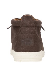 Bruine canvas enkelboot met een gestructureerde afwerking, rubberen zool en een merklabel aan de achterkant. Voorzien van vetersluiting en gezorgd voor een gemêleerde voering.
