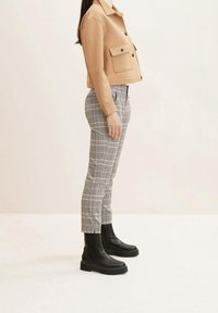 Bred croppad jacka, rutiga byxor i svart och vitt, samt svarta plattformstövlar. Noterbara egenskaper: framfickor och subtilt rutmönster.