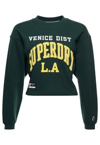 Dark green cropped sweatshirt with yellow and white "Venice Dist Superdry L.A" text and brand patches on front and sleeve.