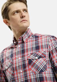 Koszula krótki rękaw w kratkę w odcieniach czerwonym, granatowym i białym, z kołnierzykiem zapinanym na guziki, dwoma kieszeniami na piersi i wzorem w kratkę na całej powierzchni.