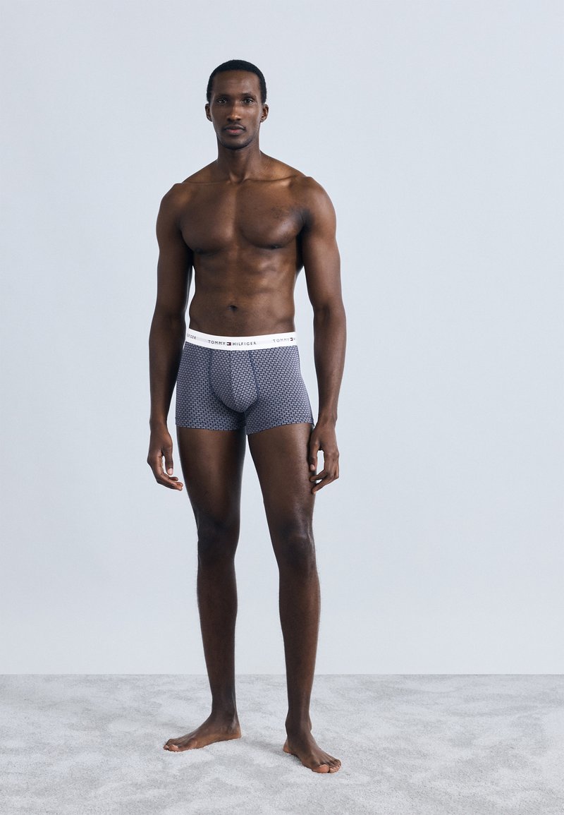 Herre boksershorts i marineblå med et geometrisk mønster, med en hvid elastisk linning. Glat stoftekstur og tætsiddende design.