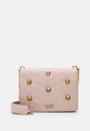 Bolso acolchado de color rosa claro con tachuelas piramidales doradas, correa de cadena y detalle de logotipo dorado en la parte inferior. Textura suave y diseño compacto.