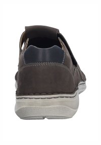 Scarpa in pelle marrone con una texture morbida, caratterizzata da un accento del tacco scuro a contrasto e una suola in gomma leggera e resistente di colore chiaro.