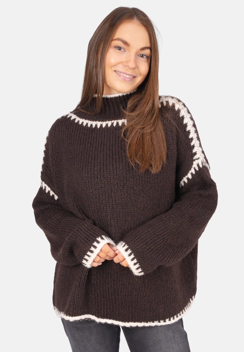 Brauner Strickpullover mit hohem Kragen, weißen gewellten Akzenten an den Bündchen und dem Saum sowie einer lockeren, übergroßen Passform.