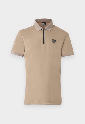 Μπεζ πόλο μπλουζάκι με κοντό φερμουάρ, μαύρες λεπτομέρειες και λογότυπο στο αριστερό στήθος. Διαθέτει απαλό, λείο ύφασμα και αντίθετο γιακά.